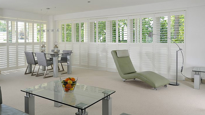 Full-height white plantation shutters in a contemporary living and dining room